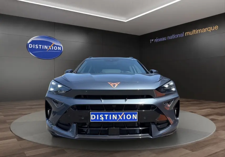 Vue avant d'un CUPRA Formentor gris foncé avec logo cuivré et phares LED allumés en showroom.
