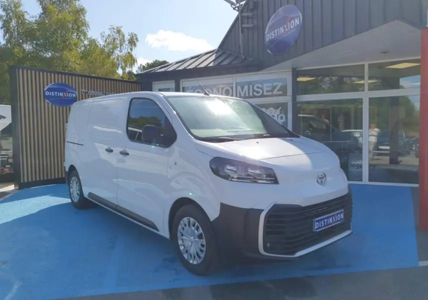 Toyota Proace Fourgon blanc Glacier vu en 3/4 avant droit sur parking bleu devant un bâtiment commercial Distinxion.