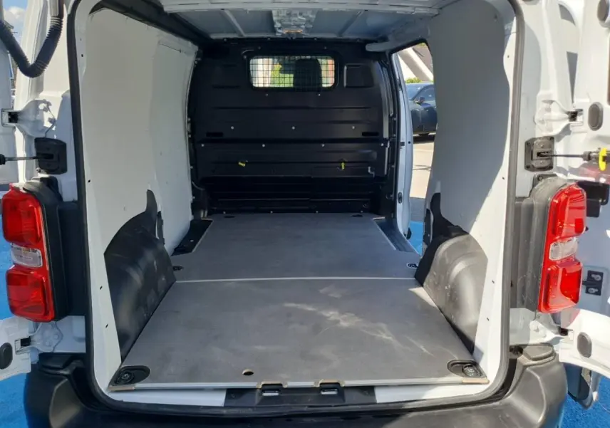Vue arrière ouverte du Toyota Proace Fourgon blanc Glacier 2025, montrant l'espace de chargement avec plancher bois et cloison pleine noire.