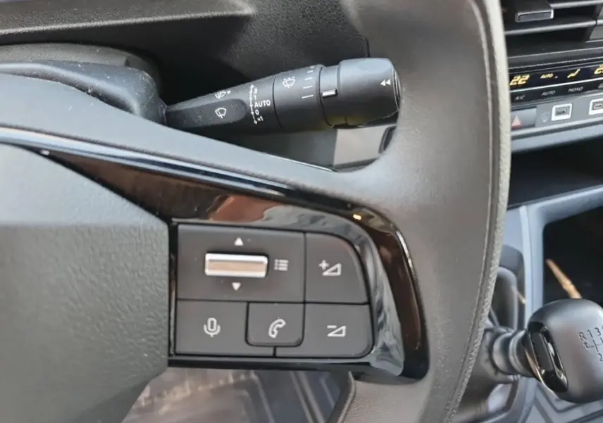 Gros plan sur les commandes au volant et levier de vitesse manuel du Toyota Proace Fourgon blanc Glacier, intérieur gris foncé.