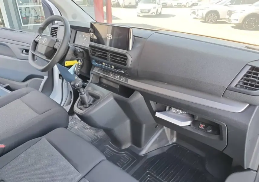 Intérieur du Toyota Proace Fourgon blanc, vue côté conducteur, tableau de bord moderne avec écran tactile et banquette 2 places.
