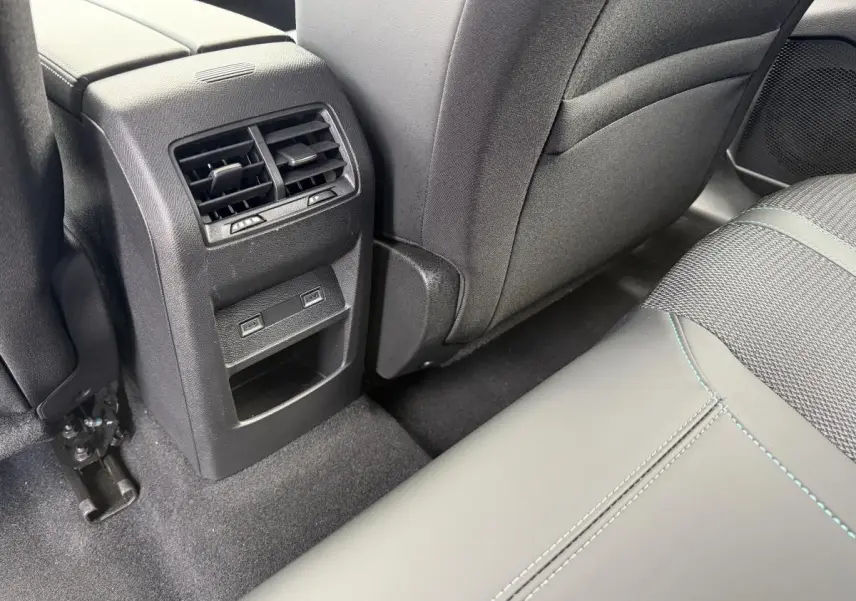 Vue rapprochée de la console arrière avec aérateurs et prises USB C, sièges gris foncé avec surpiqûres bleues Peugeot 308 SW 2024.