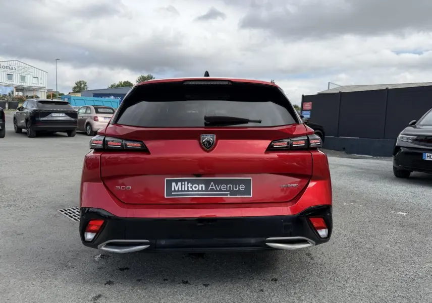 Vue arrière d’une Peugeot 308 SW hybride rouge Elixir avec feux LED et double sortie d’échappement chromée.