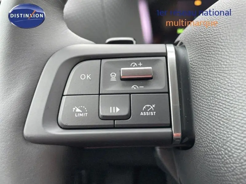 Gros plan sur les commandes de régulateur et assistant de conduite au volant cuir gris d'une Citroën C4 2024.