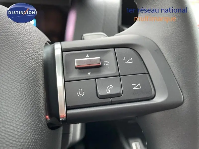 Gros plan sur les commandes vocales et téléphone au volant cuir gris d'une Citroën C4 1.2 Hybride 2024