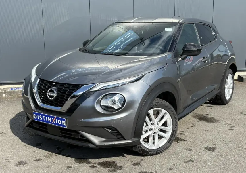 Nissan Juke gris Dark Metal en 3/4 avant droit, avec jantes alliage blanches et calandre chromée distinctive.