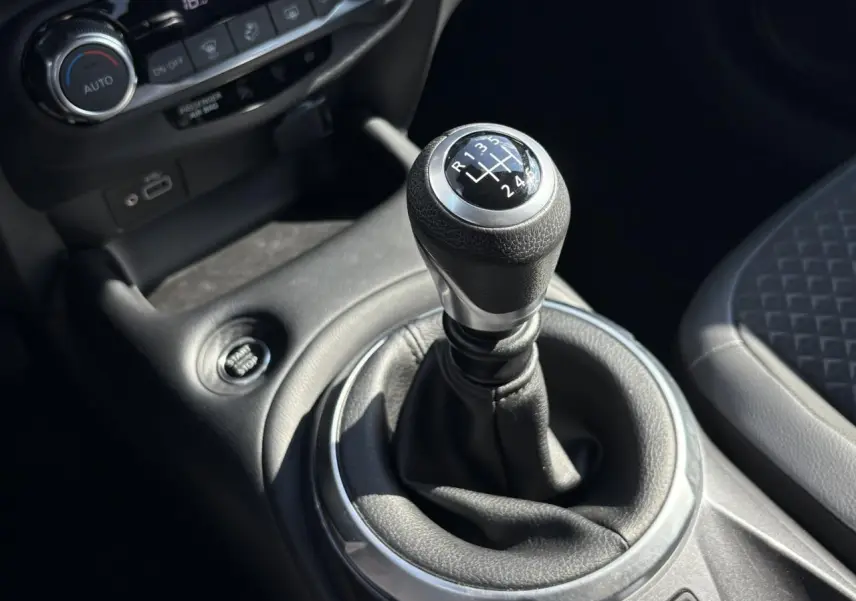 Le levier de vitesses manuel noir et argenté du Nissan Juke 2024, avec bouton Start/Stop et console centrale en cuir gris.