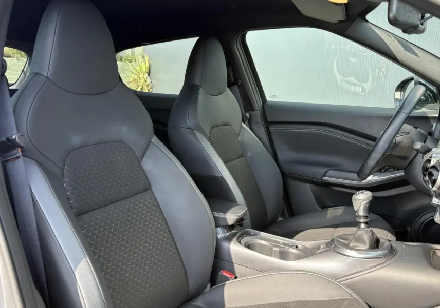 Vue intérieure côté droit du Nissan Juke 2024, sièges avant en sellerie mixte noir et gris avec levier de vitesses manuel.