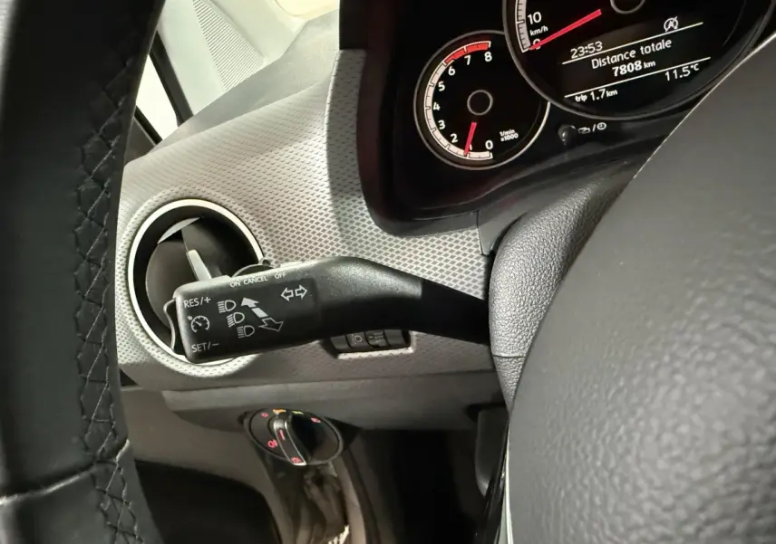 Gros plan sur le commodo gauche et le tableau de bord gris d’une Volkswagen Up 1.0 65 Active de 2022, affichage digital visible.