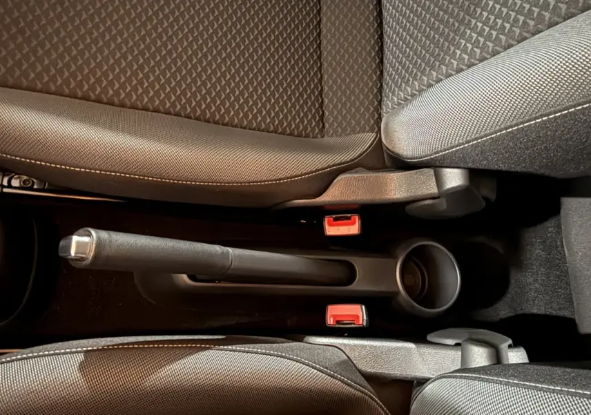 Vue rapprochée du frein à main manuel entre les sièges avant gris foncé du Volkswagen Up 1.0 65 Active.