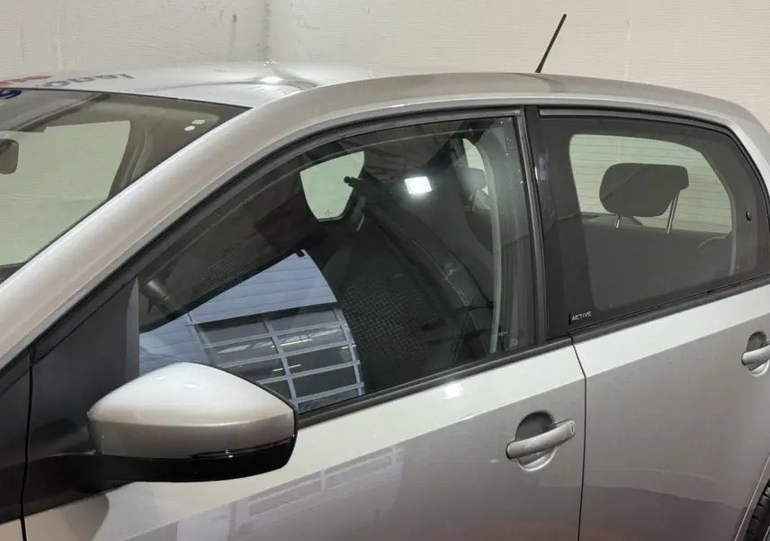 Vue latérale gauche d'une Volkswagen Up gris foncé avec badge Active sur la porte arrière et rétroviseur assorti.