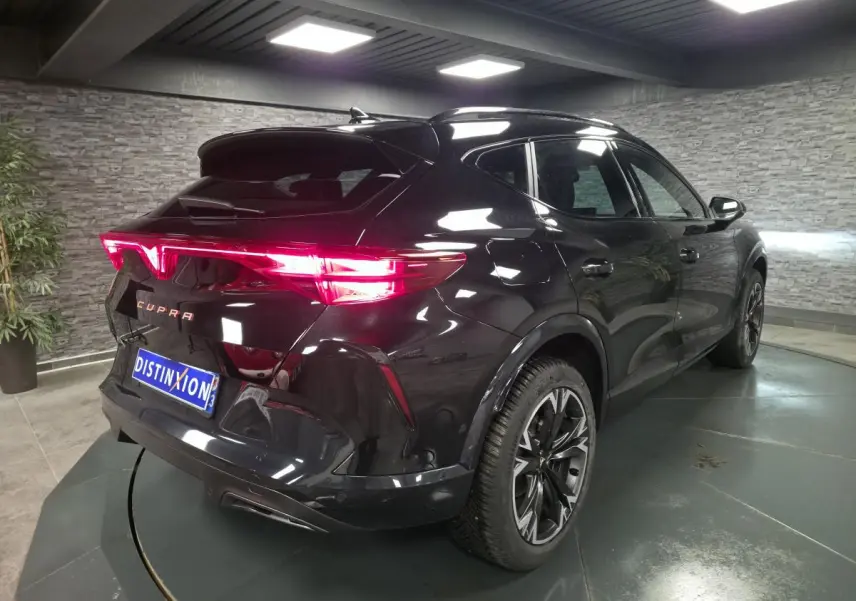 Vue 3/4 arrière droite du CUPRA Formentor noir 2025 avec feux arrière Tri-LED allumés et jantes alliage 18 pouces.
