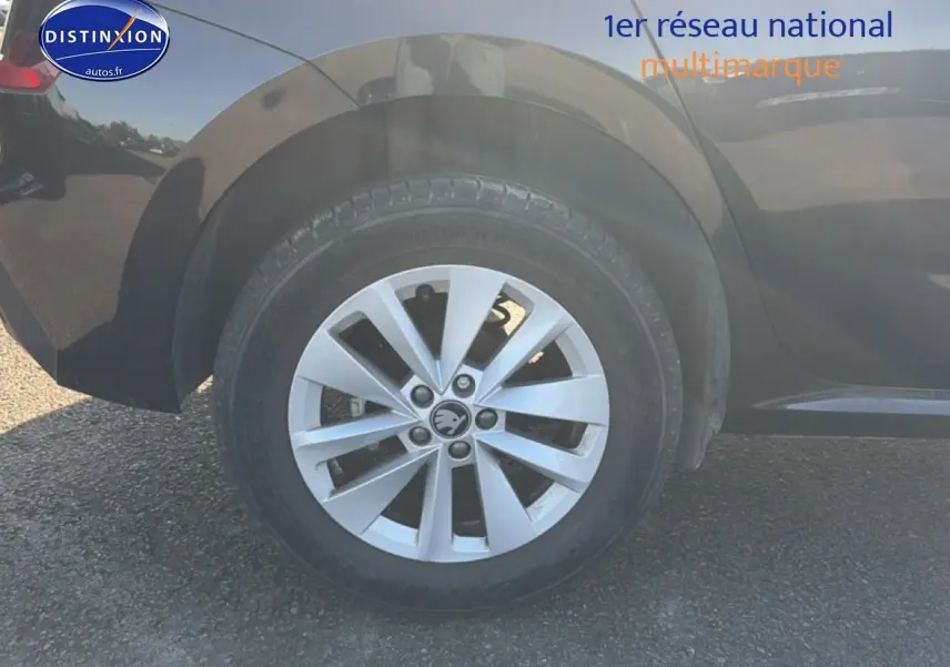 Gros plan sur la roue arrière droite d’un Skoda Kamiq noir avec jante alu et logo au centre.