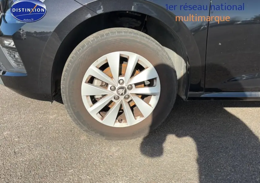 Gros plan sur la roue avant gauche d’un Skoda Kamiq noir, avec jante alu et partie avant du véhicule visible.