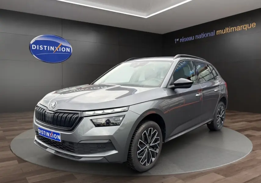 Skoda Kamiq gris foncé en 3/4 avant droit avec jantes bi-ton et calandre noire brillante dans showroom.