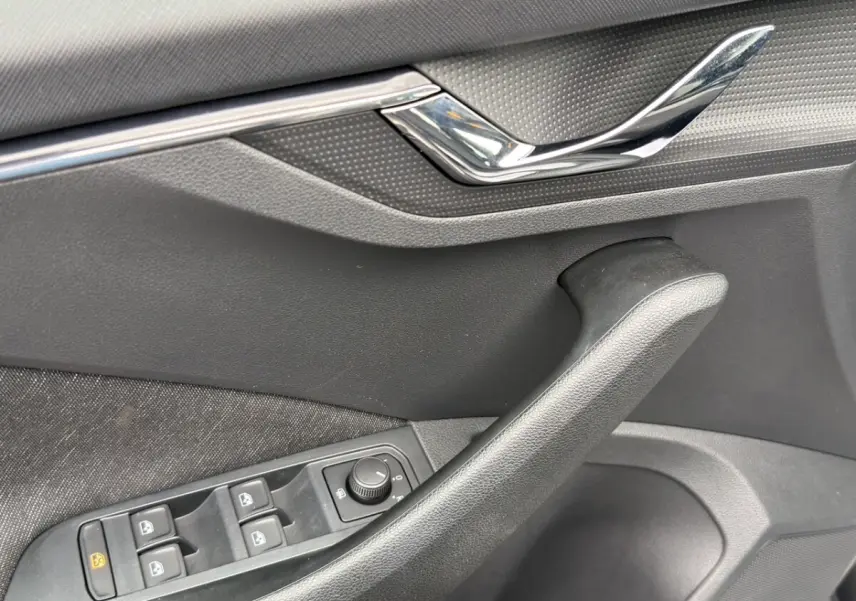 Détail de la porte côté conducteur du Skoda Kamiq gris foncé, avec commandes électriques des vitres et poignée chromée.