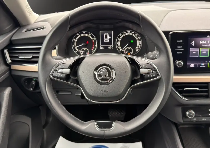 Vue centrée sur le volant cuir noir et le tableau de bord numérique du Skoda Kamiq 1.5 TSI 2023, avec écran tactile latéral.