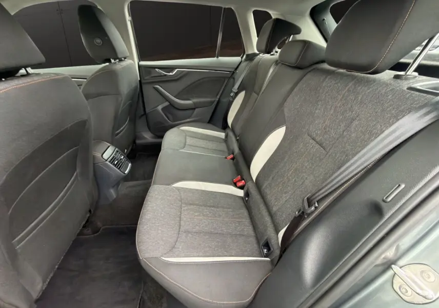 Vue intérieure arrière côté droit du Skoda Kamiq 2023, sièges tissu gris foncé avec surpiqûres orange et inserts clairs.