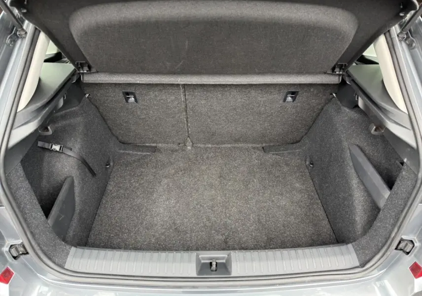 Coffre ouvert vu de l'arrière d'un Skoda Kamiq gris foncé, avec intérieur en tissu gris et espace de rangement vide.