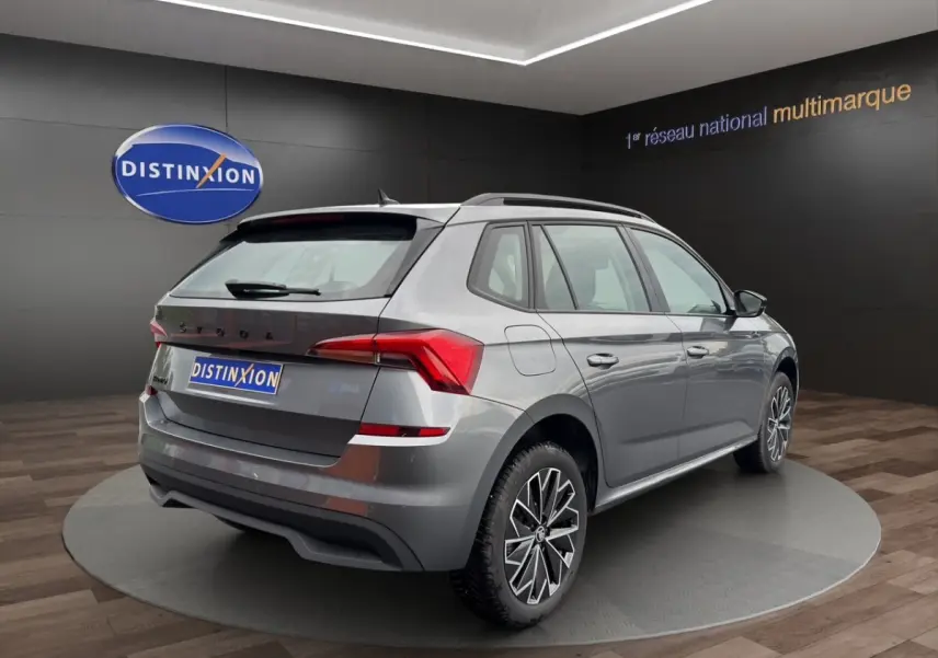 Vue 3/4 arrière droite du Skoda Kamiq gris foncé avec jantes bi-ton et feux arrière LED en showroom.
