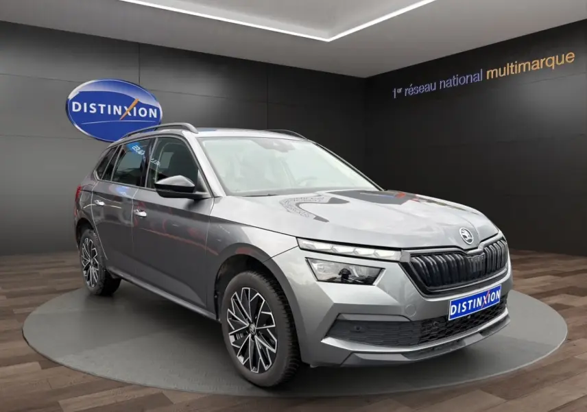 SUV Skoda Kamiq gris foncé vu en 3/4 avant droit avec jantes bi-ton et calandre noire distinctive.
