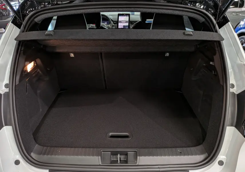 Coffre ouvert vu de l'arrière d'un Renault Captur blanc nacré avec toit noir, intérieur noir et tablette tactile visible.