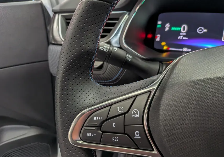 Gros plan sur le volant en cuir perforé noir du Renault Captur E-Tech 2026 avec commandes intégrées et tableau de bord numérique.