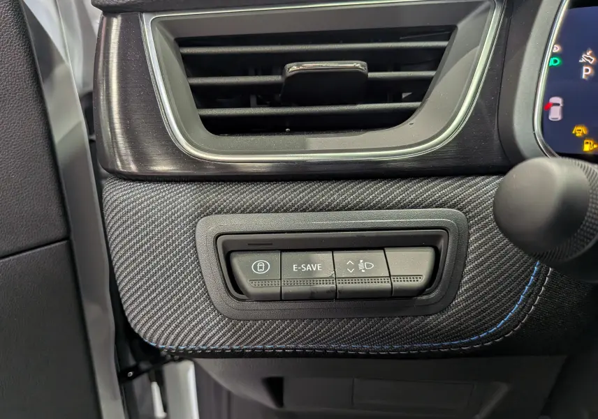 Gros plan sur la console côté conducteur du Renault Captur E-TECH blanc nacré, avec boutons de contrôle et finition carbone.