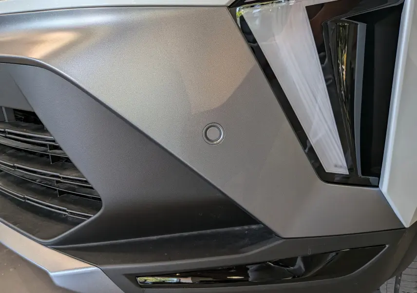 Détail du pare-chocs avant droit du Renault Captur blanc nacré avec feux LED et capteur de stationnement intégré.