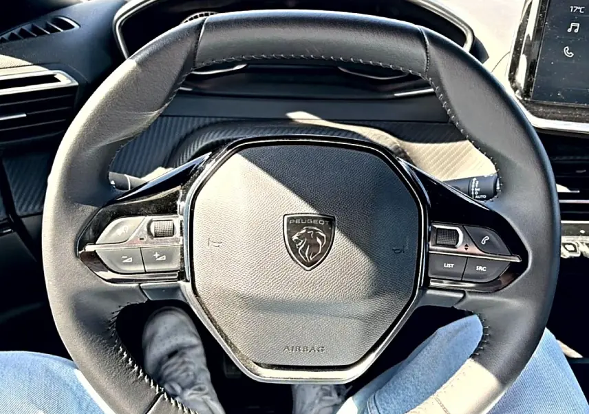 Vue rapprochée du volant noir multifonction de la Peugeot 2008 2025 avec logo lion au centre et commandes intégrées.