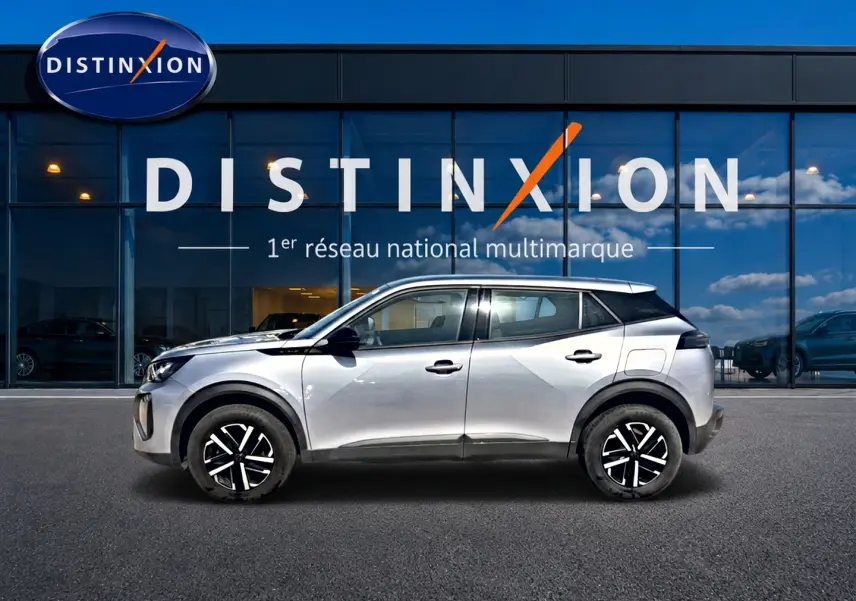 Vue de profil côté gauche d'un Peugeot 2008 gris 2025 avec jantes noires et toit blanc devant une vitrine Distinxion.