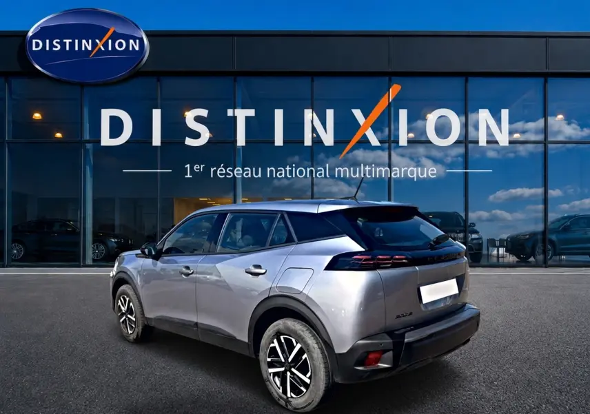 Peugeot 2008 gris en 3/4 arrière droit, avec feux arrière LED et becquet, devant une vitrine Distinxion.