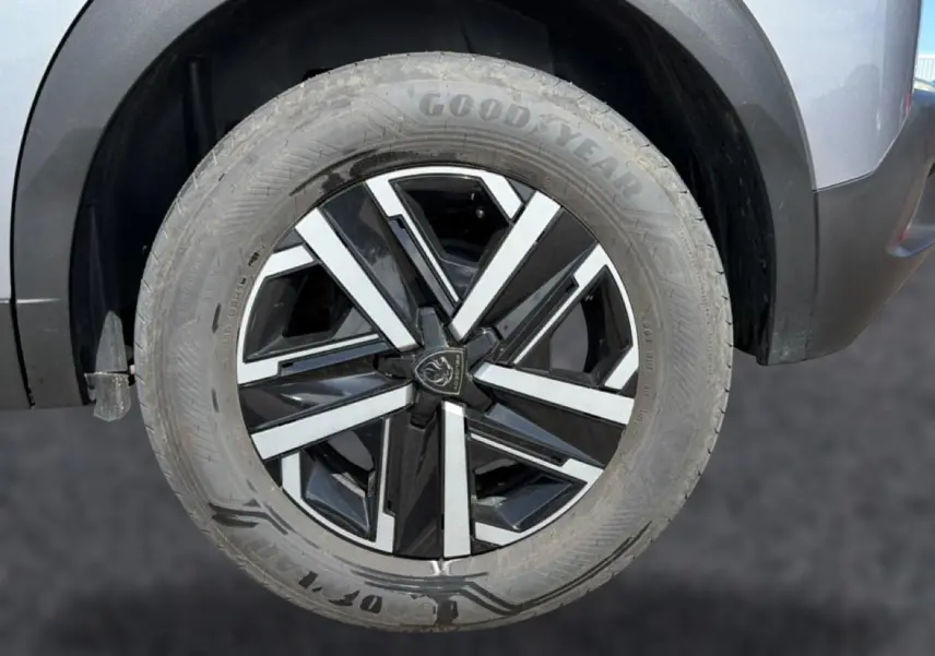 Gros plan sur la roue avant droite d’un Peugeot 2008 gris avec jante noire et argentée au design moderne.