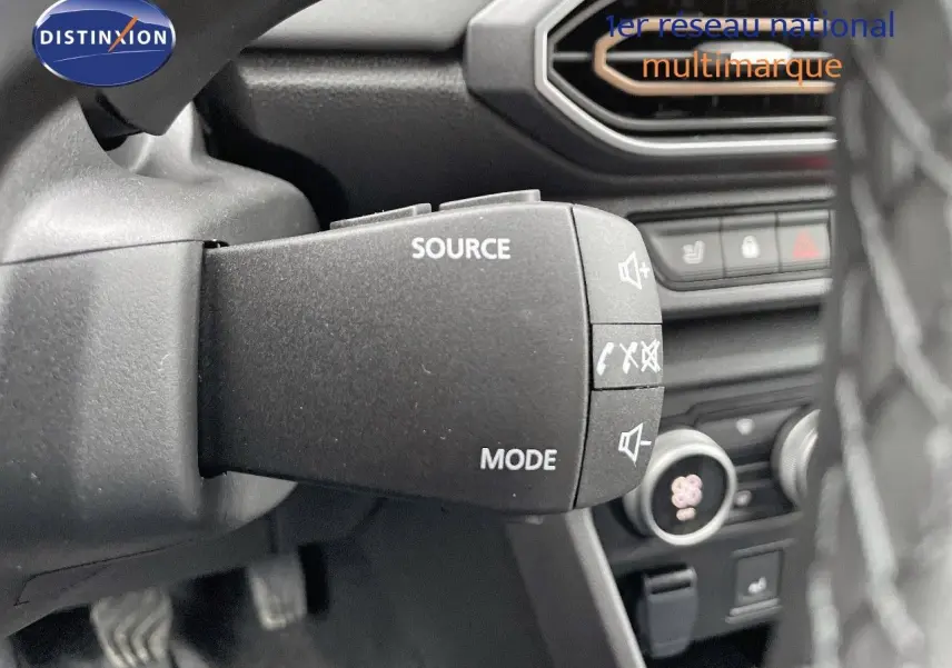 Gros plan sur la commande audio au volant du Dacia Jogger 2024, intérieur noir avec détails des boutons source et mode.