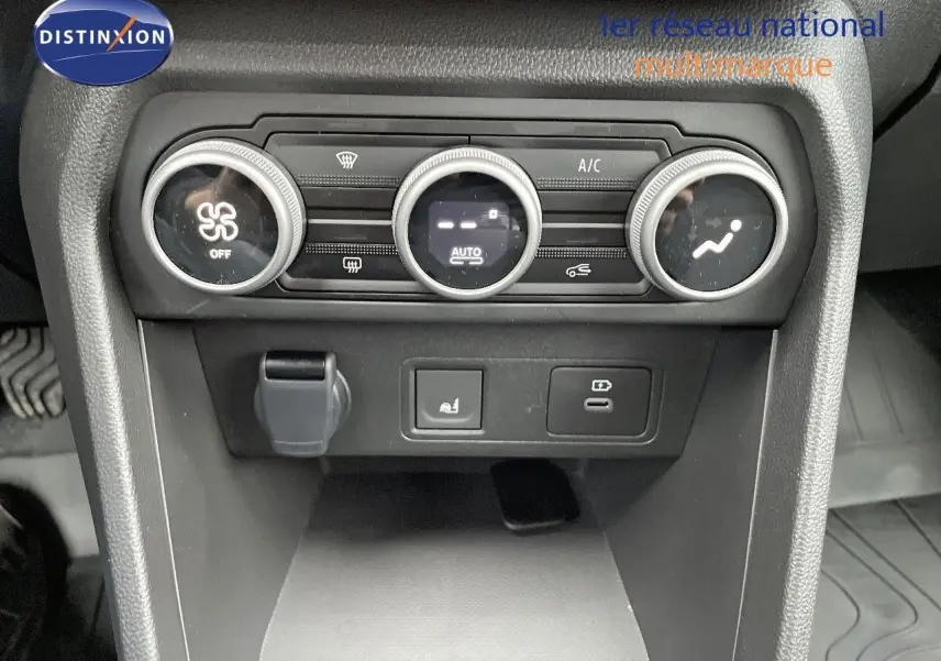 Vue rapprochée de la console centrale noire du Dacia Jogger 2024, avec commandes de climatisation et prises USB.