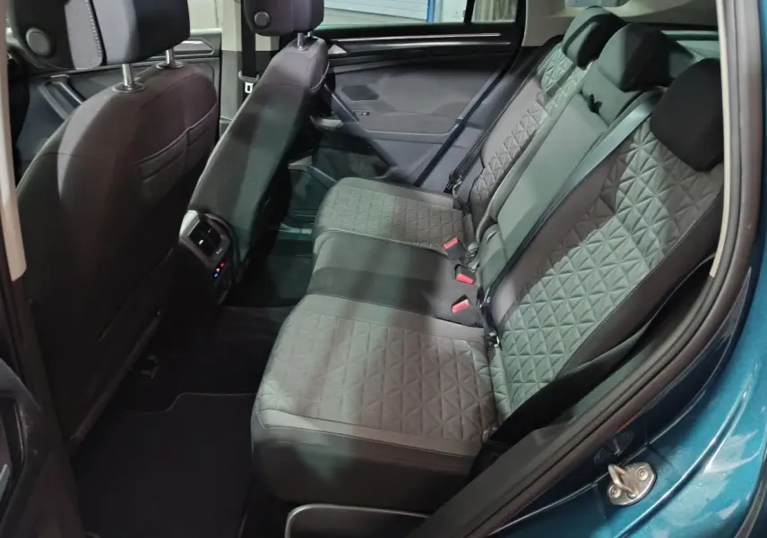 Vue intérieure côté droit sur la banquette arrière grise du Volkswagen Tiguan bleu, avec détails de la porte et sièges.