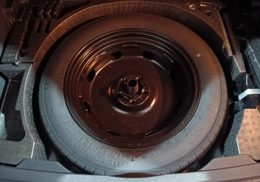 Gros plan sur la roue de secours noire dans le coffre du Volkswagen Tiguan 2021, version Life Business bleu.