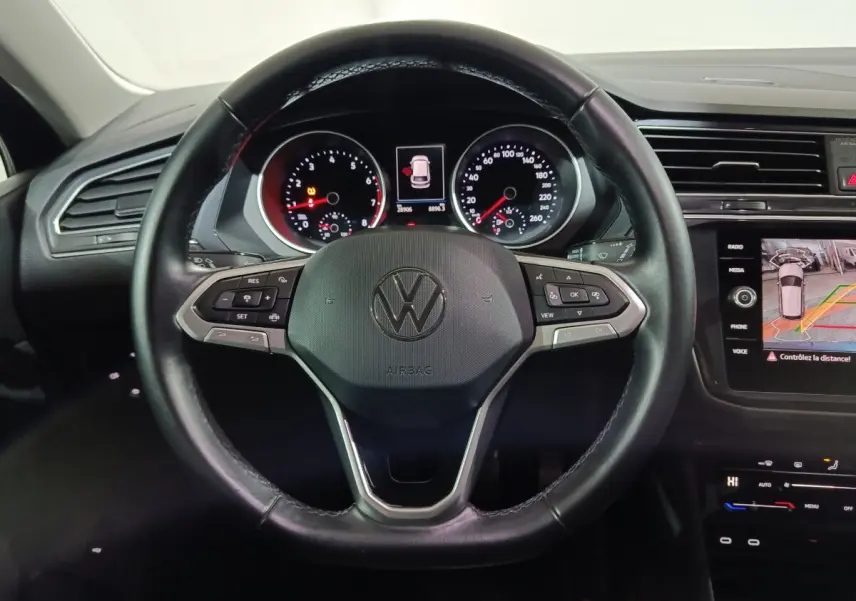 Vue rapprochée du volant cuir multifonctions noir du Volkswagen Tiguan 2021 avec tableau de bord et écran tactile.