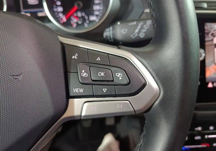 Gros plan sur le volant cuir noir multifonctions du Volkswagen Tiguan 2021, avec commandes intégrées et tableau de bord partiel.