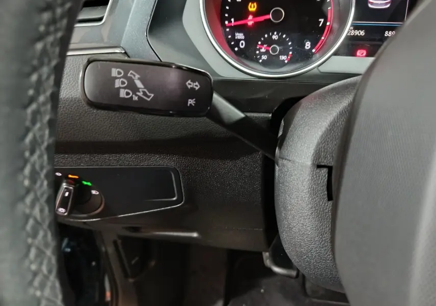 Gros plan sur le commodo gauche du volant noir d’un Volkswagen Tiguan 1.5 TSI 2021, avec tableau de bord partiel visible.