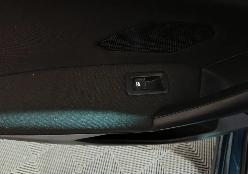 Détail de la poignée intérieure de porte côté gauche du Volkswagen Tiguan bleu, avec bouton de verrouillage éclairé.