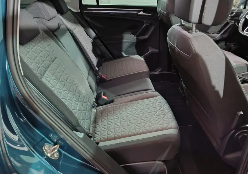 Vue intérieure côté arrière droit du Volkswagen Tiguan bleu 2021, montrant les sièges arrière en tissu gris à motif géométrique.