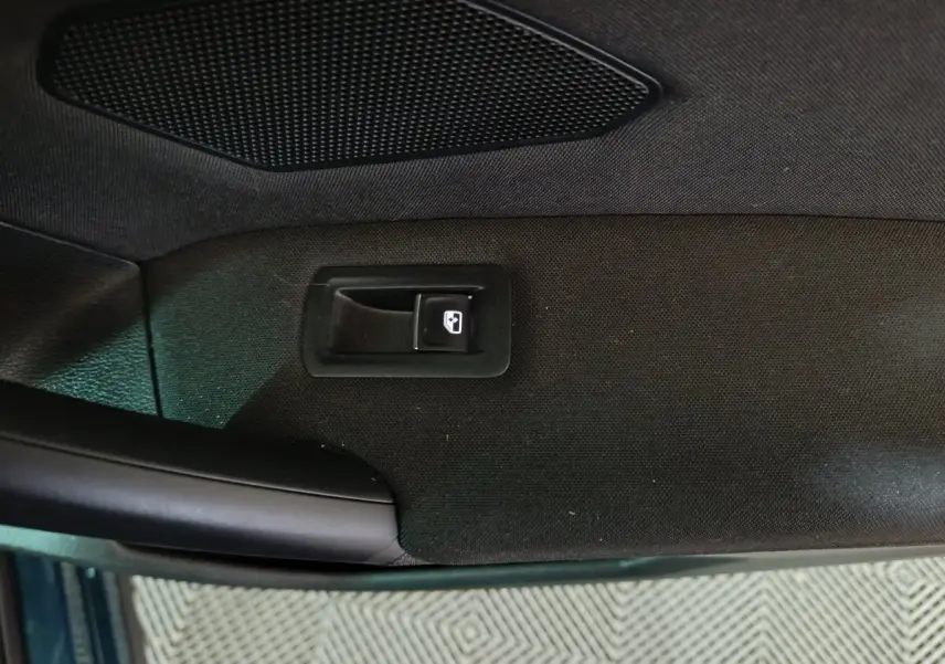 Vue rapprochée de la poignée intérieure et bouton de lève-vitre sur la porte côté conducteur du Volkswagen Tiguan bleu.