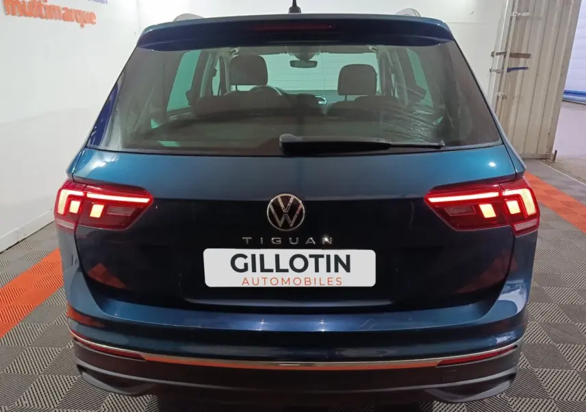 Vue arrière d'un Volkswagen Tiguan bleu 2021 avec feux arrière LED allumés dans un garage.