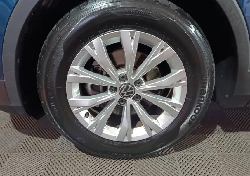 Gros plan sur la roue avant droite du Volkswagen Tiguan bleu, mettant en valeur la jante alliage argentée et le pneu Hankook.