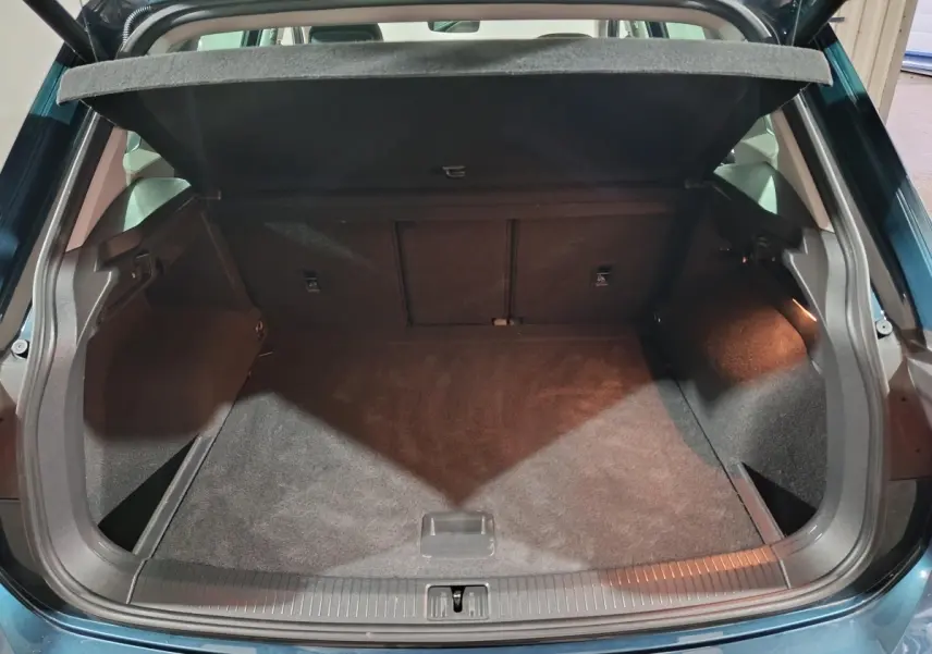 Vue arrière du coffre ouvert du Volkswagen Tiguan bleu 2021, montrant un espace de rangement propre et spacieux.