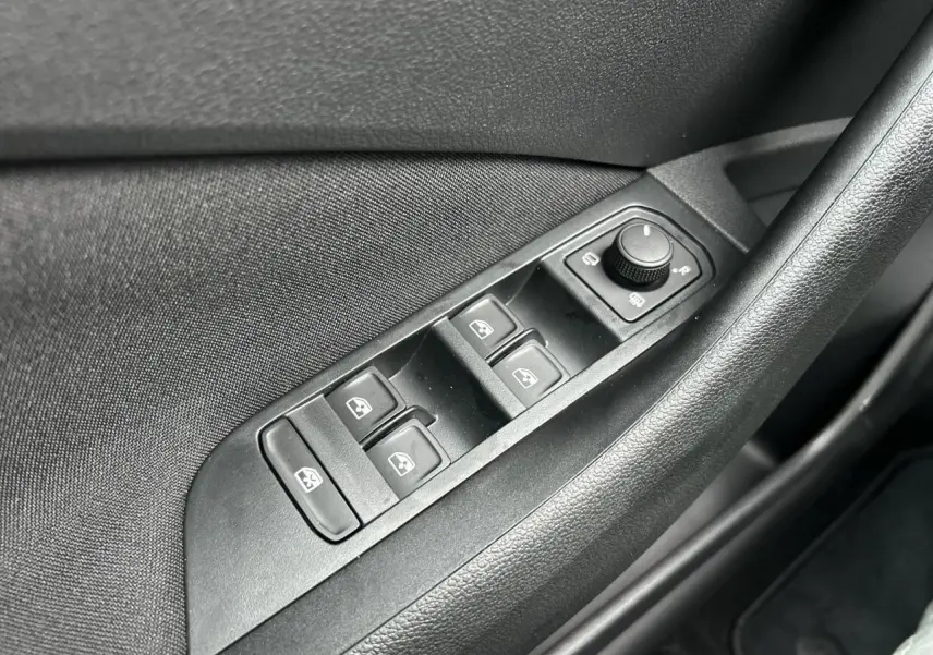 Gros plan sur les commandes de lève-vitres et réglage des rétroviseurs côté conducteur d’un Skoda Kamiq noir Magic.