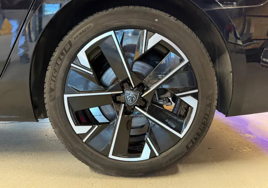 Gros plan sur la jante alliage 18'' bi-ton diamantée noire et argentée du côté arrière droit d'une Peugeot 508 SW noire.