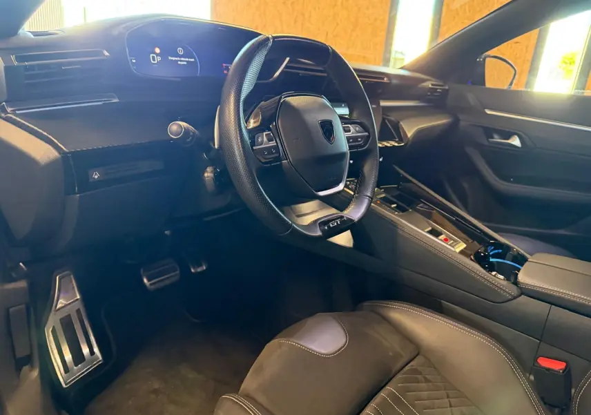 Vue intérieure côté conducteur du Peugeot 508 SW noir, volant GT cuir perforé et planche de bord avec écran numérique.