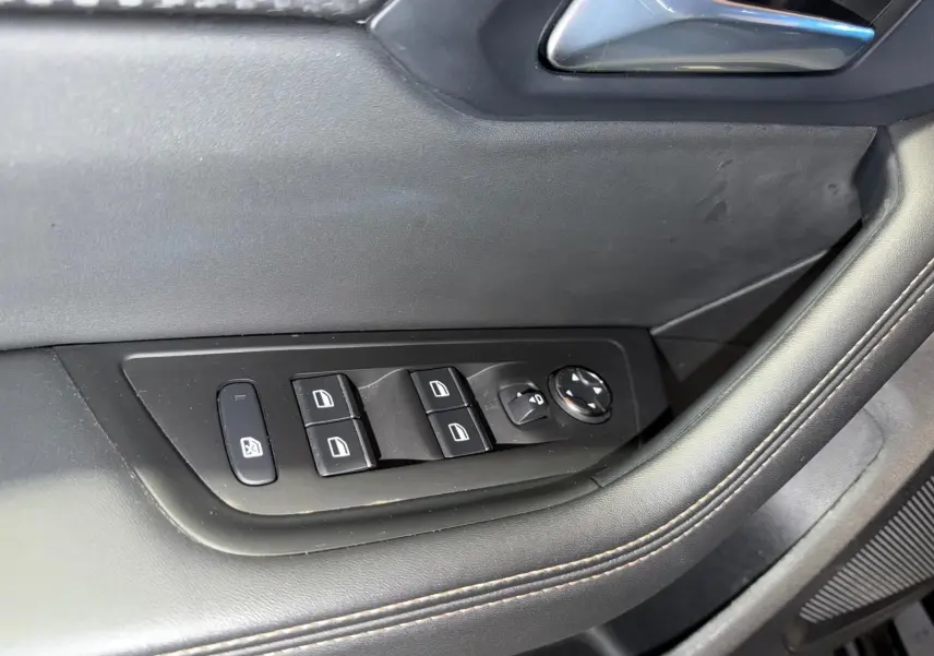 Détail des commandes de lève-vitres et rétroviseurs sur la porte côté conducteur d’un Peugeot 508 SW noir.